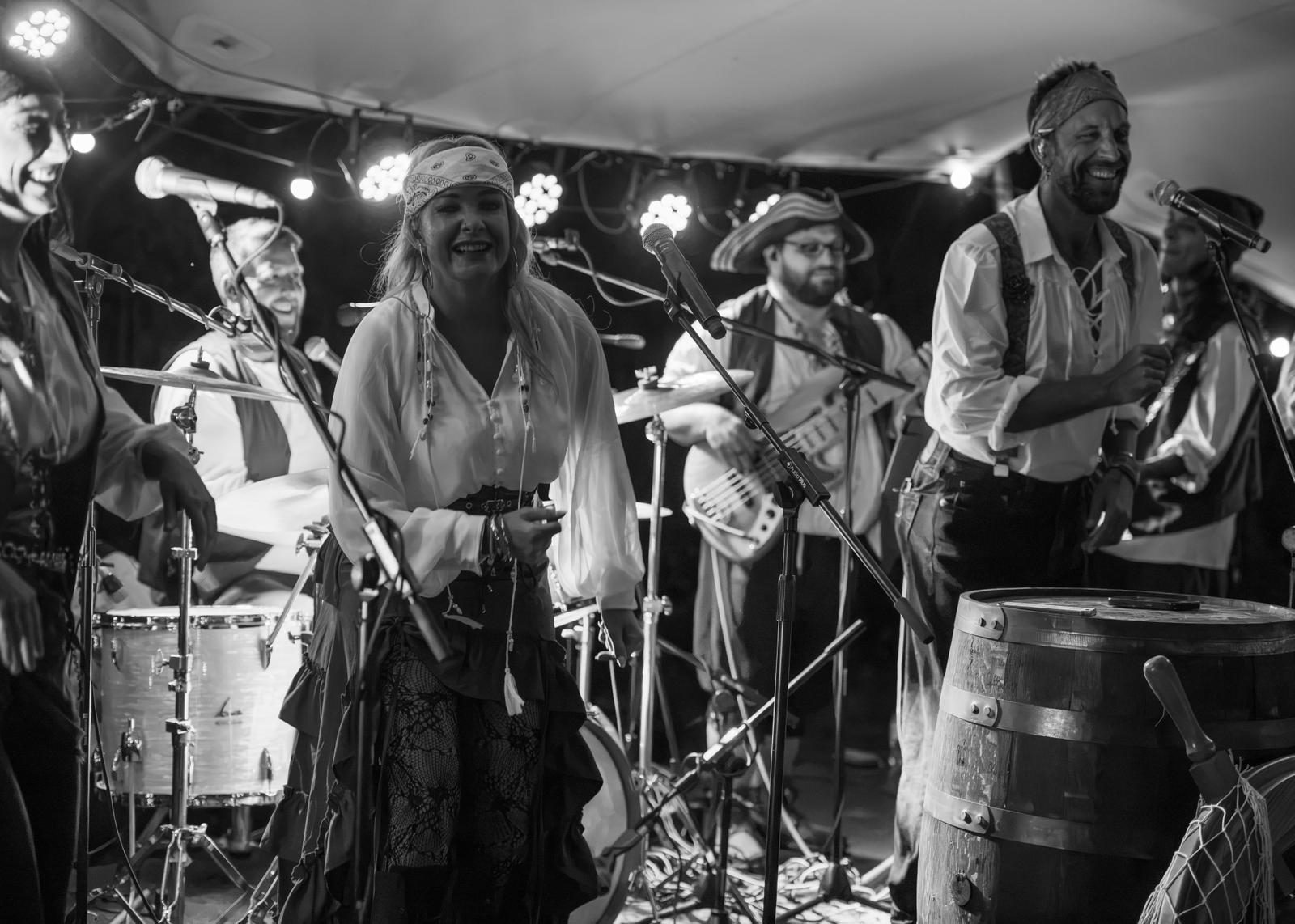 The band laughing between songs beside the drums and a wooden barrel