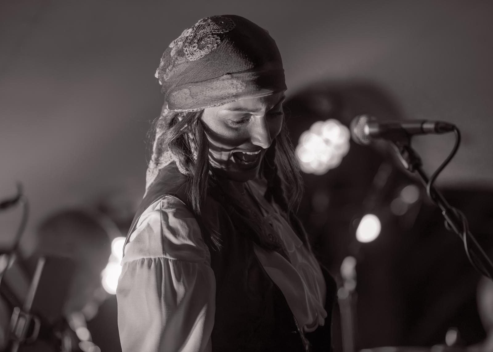 A shipmate in a bandana looking down with stage lights glowing behind
